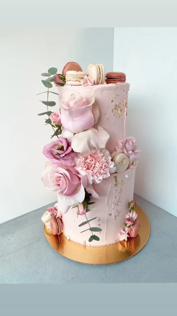 Pink tiered cake with macarons and roses