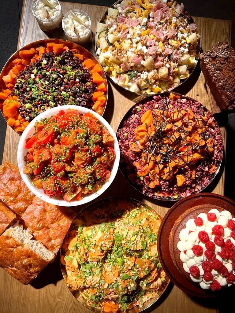 A lunch spread of salads and a pavlova